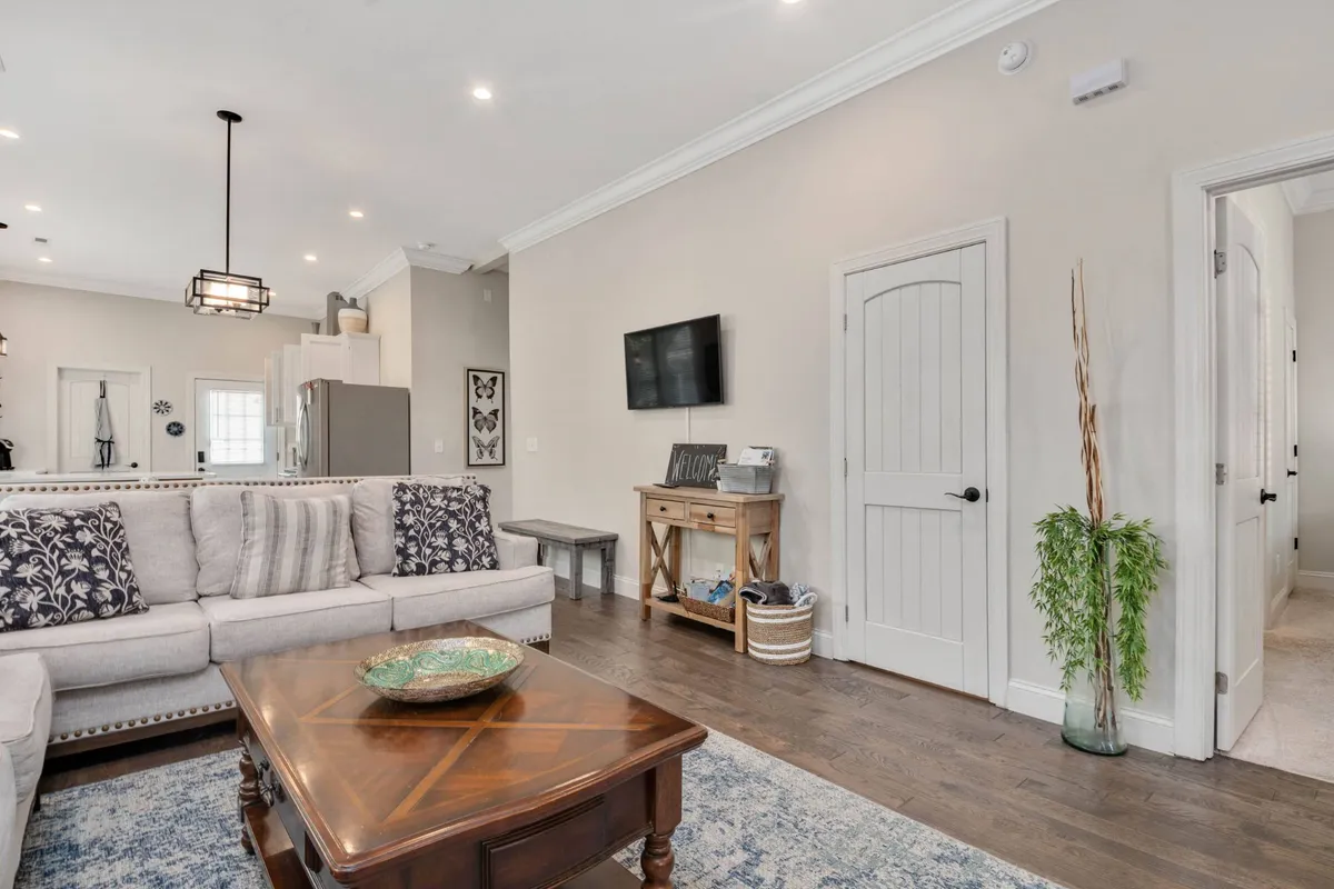 A cozy living room with a comfortable sofa, wooden coffee table, decorative wall art, and a TV unit. The layout is spacious, ideal for groups to gather. The inviting decor and smart TV setup encourage socializing, movie nights, and relaxation.