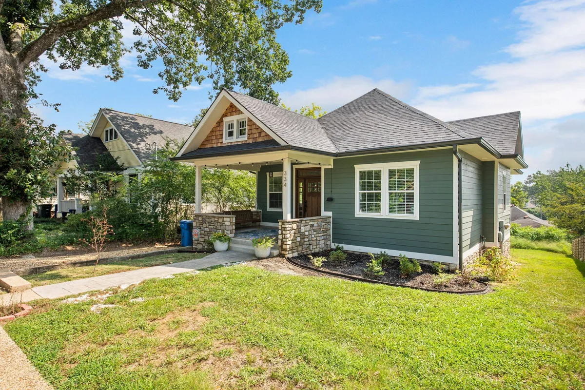 A welcoming front porch with stone accents, attractive landscaping, and detailed windows, evoking a sense of arrival and relaxation in a friendly neighborhood setting.